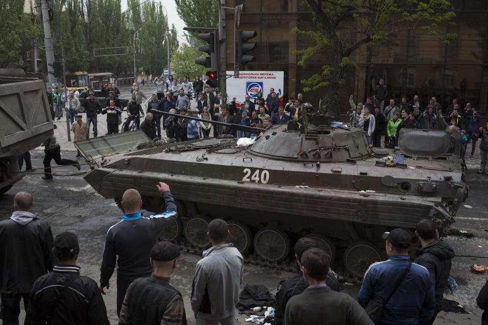 People gather around a Ukrainian government forces armored personal carrier seized by pro-Russia insurgents during fighting in Mariupol, eastern Ukraine, Friday, May 9, 2014. In Ukraine’s east, where pro-Russia insurgents have seized government buildings and fought with Ukrainian forces, fatal fighting broke out in the city of Mariupol. The country’s Interior Minister said around 20 “terrorists” and one policeman were killed. (AP Photo/Alexander Zemlianichenko)