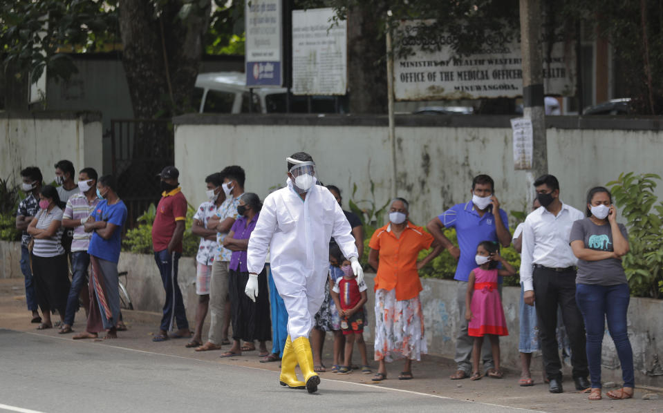 Sri Lankans wait to give swab samples to test for COVID-19 outside a hospital as a health official walks past in Minuwangoda, Sri Lanka, Tuesday, Oct. 6, 2020. (AP Photo/Eranga Jayawardena)