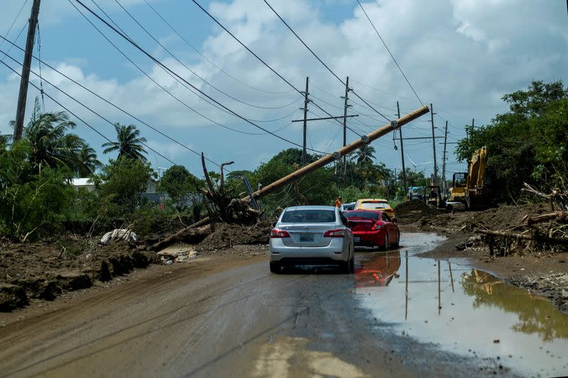 FOTO DE ARCHIVO: Unos coches pasan por debajo de un poste eléctrico derribado tras el paso del huracán Fiona en Santa Isabel