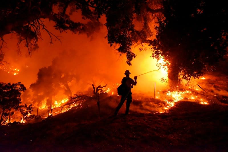 Santa Barbara City firefighter Erik Adair battles flames near a home off Cieneguitas Rd in Santa Barbara, California