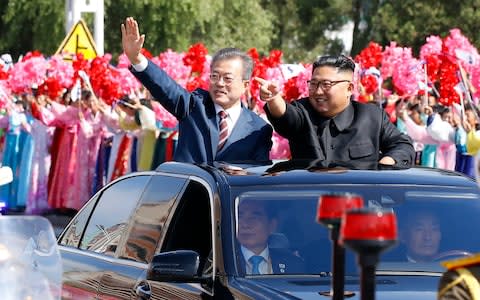 Kim Jong Un and South Korean President Moon Jae-in wave to Pyongyang citizens from an open-topped as they drive through Pyongyang on September 18 - Credit: AFP