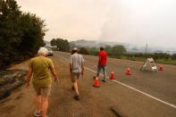 Evacuated residents Esther Brunswick, her husband Ron Brunswick, and Chris Hale walk away from a police checkpoint after trying to check on their homes, in Deer Park, California