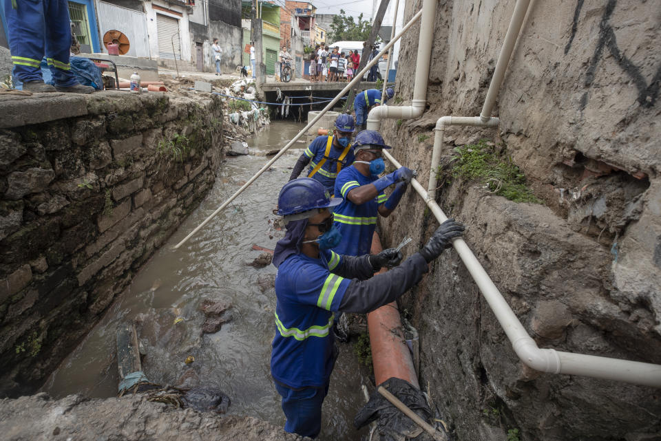 Operarios trabajan en la instalación de un sistema de recogida de aguas residuales en la comunidad de Americanopolis, cerca del río Pinheiros, en Sao Paulo, Brasil, el 22 de octubre de 2020. Tras años afectado por vertidos de aguas residuales y basura, el gobierno estatal de Sao Paulo está intentando de nuevo limpiar el río Pinheiros, considerado uno de los más contaminados del país. (AP Foto/Andre Penner)