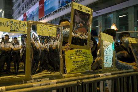 Police officers are reflected on reflective materials held by a pro-democracy protesters on a blocked road at Mongkok shopping district in Hong Kong October 19, 2014. REUTERS/Tyrone Siu