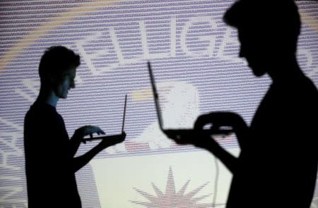 FILE PHOTO: People are silhouetted as they pose with laptops in front of a screen projected with binary code and a Central Inteligence Agency (CIA) emblem, in this picture illustration taken in Zenica, Bosnia and Herzegovina October 29, 2014. REUTERS/Dado Ruvic/File Photo/Illustration