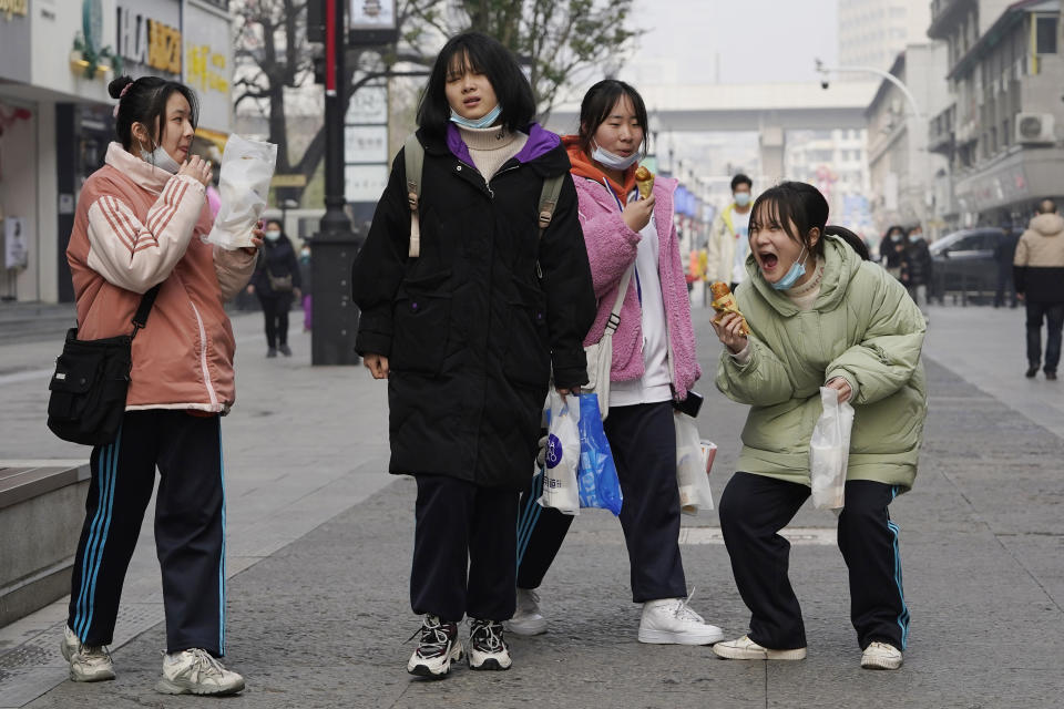 Young girls enjoy a light moment as they visit a popular shopping street in Wuhan in central China's Hubei province on Tuesday, Jan. 26, 2021. The central Chinese city of Wuhan, where the coronavirus was first detected, has largely returned to normal but is on heightened alert against a resurgence as China battles outbreaks elsewhere in the country. (AP Photo/Ng Han Guan)