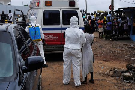 Health workers bring a woman suspected of having contracted Ebola virus to an ambulance in front of a crowd in Monrovia, Liberia, September 15, 2014. REUTERS/James Giahyue