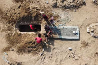 In this May 21, 2020, photo, grave diggers bury a body at Radwan Cemetery in Aden, Yemen. At a cemetery in Yemen’s largest southern city, dozens of fresh graves are a testament to a spike in deaths amid the coronavirus pandemic. The cemetery workers who bury them don’t know what killed the newly deceased. But there’s no denying that there's been an increasing number of people getting sick in the port city of Aden — likely from the coronavirus. (AP Photo)