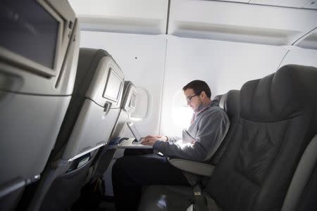 FILE PHOTO: A man uses his laptop to test a new high speed inflight Internet service named Fli-Fi while on a special JetBlue media flight out of John F. Kennedy International Airport in New York in this December 11, 2013 file picture. REUTERS/Lucas Jackson/Files/File Photo