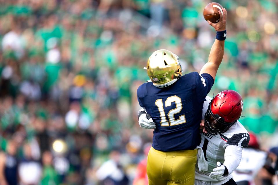 Cincinnati Bearcats defensive lineman Myjai Sanders (21) hits Notre Dame Fighting Irish defensive lineman Jordan Botelho (12) as he throws an interception made by Cincinnati Bearcats linebacker Deshawn Pace (20) in the first half of the NCAA football game between the Cincinnati Bearcats and the Notre Dame Fighting Irish on Saturday, Oct. 2, 2021, at Notre Dame Stadium in South Bend, Ind. 