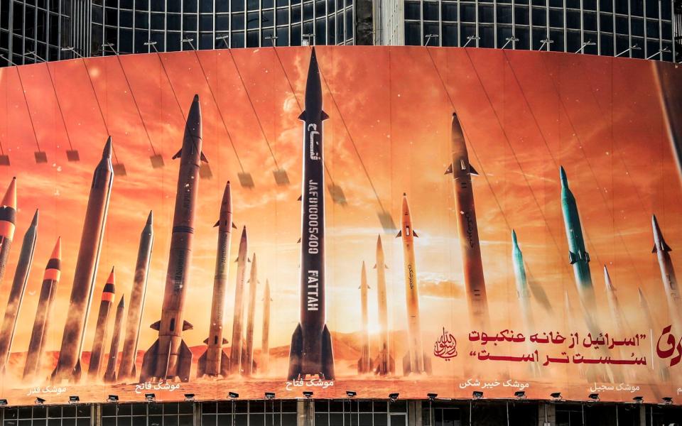 A billboard depicting named Iranian ballistic missiles in service, with text in Arabic reading 'the honest [person's] promise' and in Persian 'Israel is weaker than a spider's web', in Valiasr Square in central Tehran