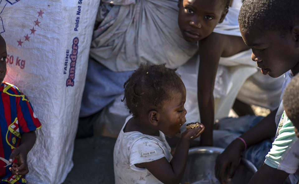 A child eats a handful of grain from a pot at the Hugo Chavez public square transformed into a refuge for families forced to leave their homes due to clashes between armed gangs in Port-au-Prince, Haiti, Thursday, Oct. 20, 2022. (AP Photo/ Ramon Espinosa)