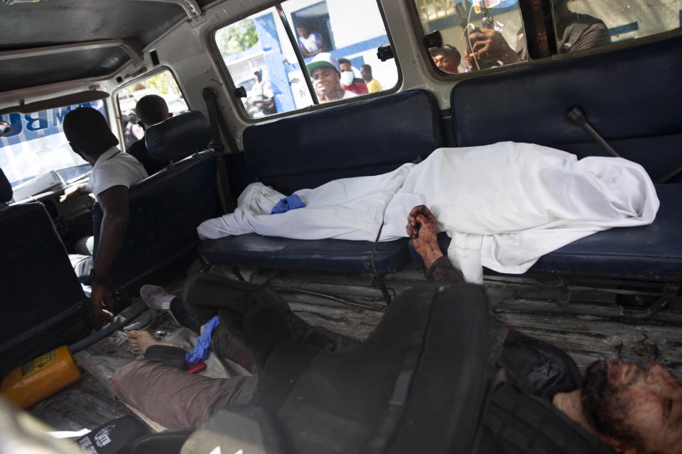 People look into the window of a police vehicle carrying the bodies of two people killed in a shootout with police in Port-au-Prince, Haiti, Thursday, July 8, 2021. According to Police Chief Leon Charles, the two dead are suspects in the assassination of Haitian President Jovenel Moïse. (AP Photo/Joseph Odelyn)