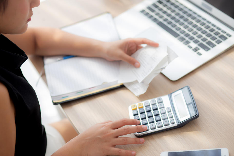 closeup hand woman calculating expenses household and writing notebook on desk, girl checking bill and stress and note, female worry debt and tax, finance and business concept.