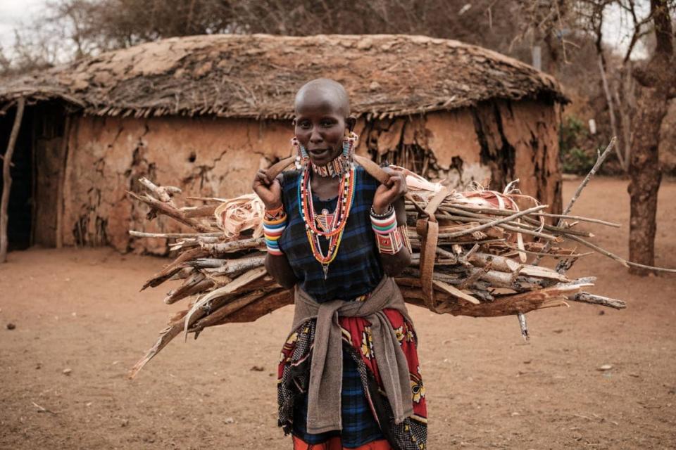 A Maasai woman arrives with collected firewood at a village nearby Selenkay Conservancy, a community-owned conservation area run by a private company, in Amboseli, Kenya, on June 22, 2022. The camp’s 10 luxurious tents see tourists flocking again, after the shutdown linked to COVID-19. (Photo by YASUYOSHI CHIBA/AFP via Getty Images)