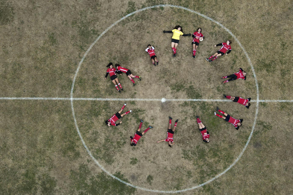 Candelaria Cabrera, top right, holds a ball as she and her soccer team Huracán de Chabas female pose for photos on the field prior to their match against Alumni in Arequito, Santa Fe province, Argentina, Monday, June 19, 2023. Candelaria’s struggle to keep playing was a turning point in Argentina’s women’s soccer. (AP Photo/Natacha Pisarenko)