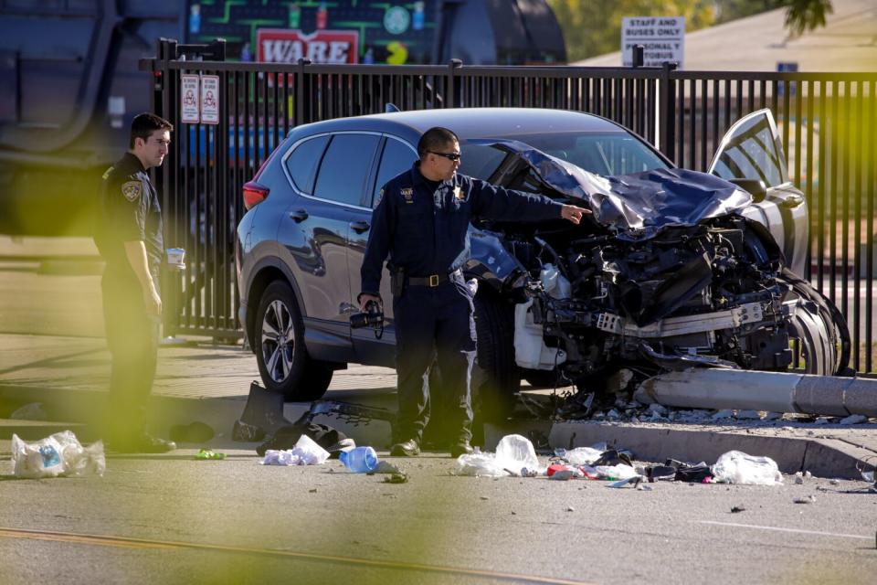 Police survey the scene next to a crashed car