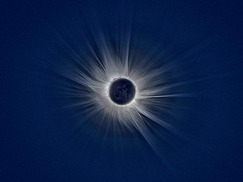The sun's corona appears as thin, white whips against a blue background.