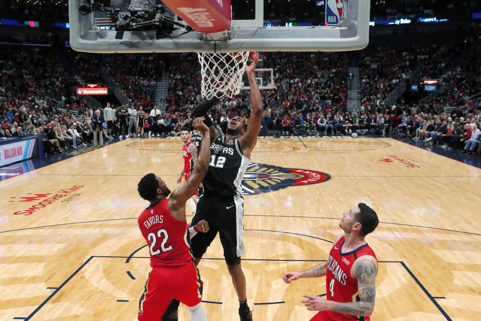 San Antonio Spurs center LaMarcus Aldridge (12) goes to the basket between New Orleans Pelicans forward Derrick Favors (22) and guard JJ Redick (4) in the first half of an NBA basketball game in New Orleans, Wednesday, Jan. 22, 2020. (AP Photo/Gerald Herbert)