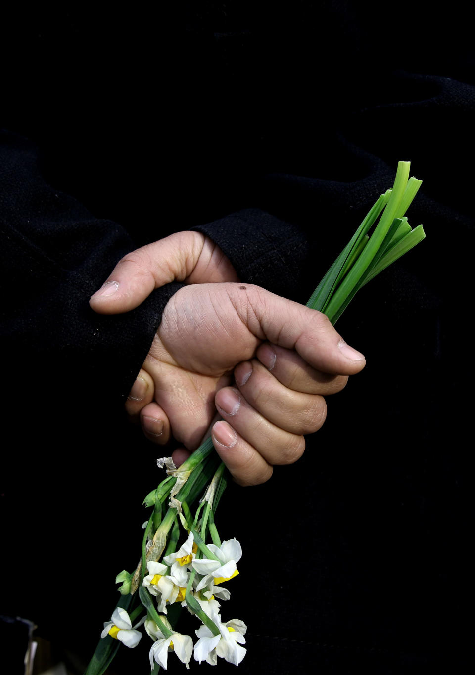 An Afghan member of a civil society organization holds flowers outside of the La Taverna du Liban restaurant, during an anti terrorism demonstration in Kabul, Afghanistan, Sunday, Jan. 19, 2014. Hundreds of Afghans gathered outside a Lebanese restaurant in Kabul on Sunday to protest against Taliban attack that killed 21 people. The assault Friday by a Taliban bomber and two gunmen against the La Taverna du Liban restaurant was deadliest single attack against foreign civilians in the course of a nearly 13-year U.S.-led war there now approaching its end. They chanted slogans against terrorism as they laid flowers at the site of the attack. The dead included 13 foreigners and eight Afghans, all civilians. The attack came as security has been deteriorating and apprehension has been growing among Afghans over their country's future as U.S.-led foreign forces prepare for a final withdrawal at the end of the year. (AP Photo/Massoud Hossaini)