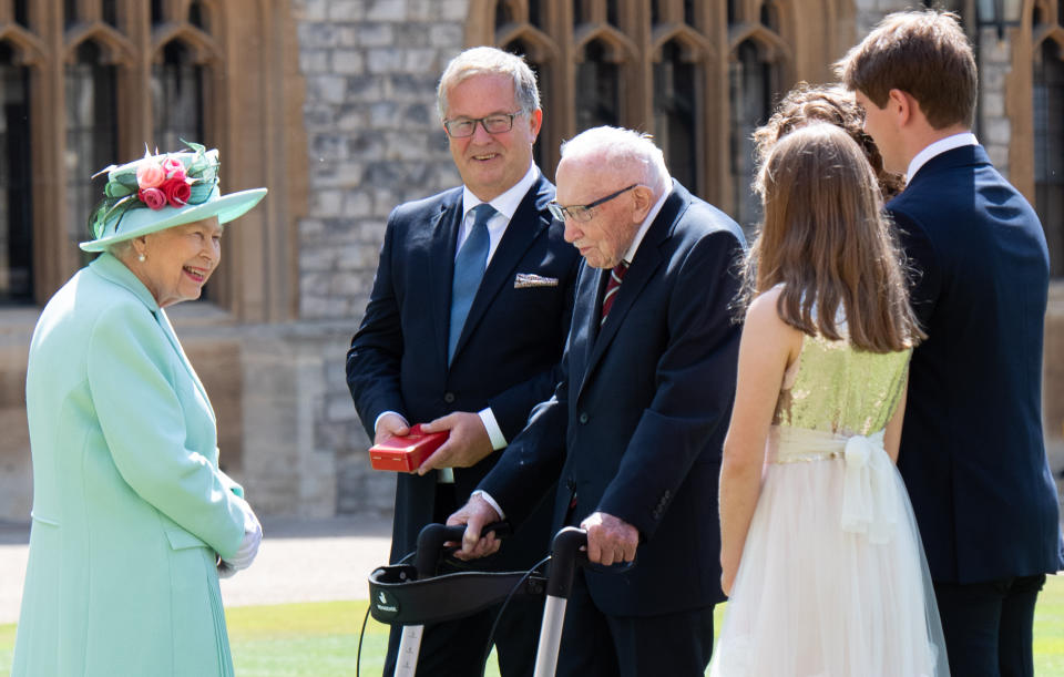 WINDSOR, ENGLAND - JULY 17: Queen Elizabeth II talks with Captain Sir Thomas Moore and his family after presenting him with the insignia of Knight Bachelor during an investiture ceremony at Windsor Castle on July 17, 2020 in Windsor, England.  British World War II veteran Captain Tom Moore raised over £32 million for the NHS during the coronavirus pandemic.  (Photo by Pool/Samir Hussein/WireImage)