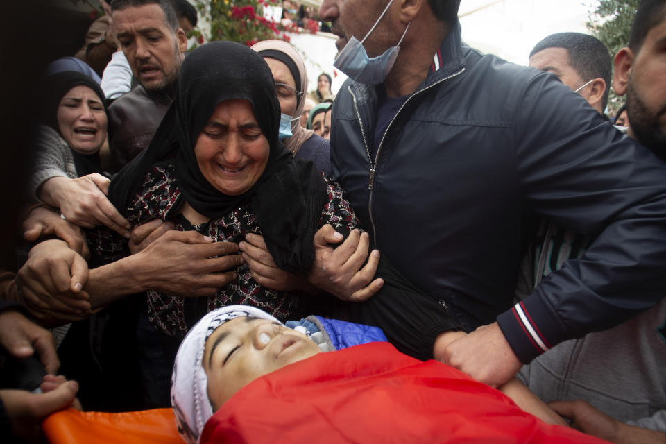 Relatives mourn the body of a 13-year-old Ali Abu Alia who was shot dead by Israeli military forces during clashes with a stone-throwing Palestinains during his funeral in al-Mughair village near the West Bank city of Ramallah, Saturday, Dec. 5, 2020. (AP Photo/Majdi Mohammed)