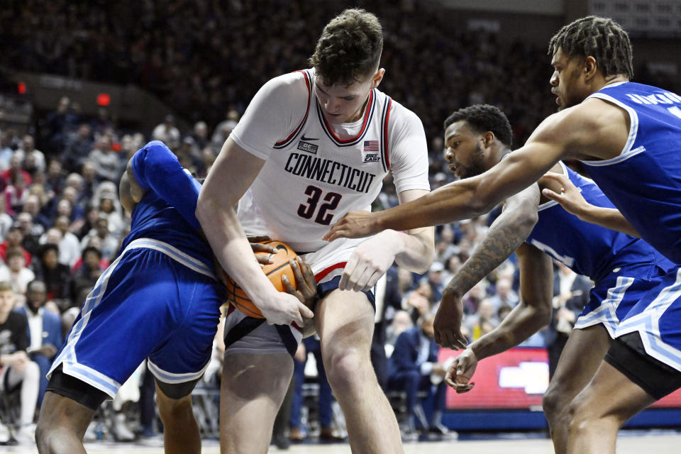 Seton Hall's KC Ndefo, right, reaches between the legs of UConn's Donovan Clingan (32) to grab the ball in the second half of an NCAA college basketball game, Saturday, Feb. 18, 2023, in Storrs, Conn. (AP Photo/Jessica Hill)