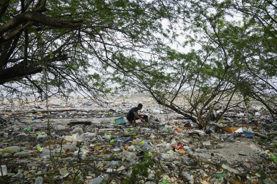 FILE - A man collects items along a polluted coastal area in Metro Manila, Philippines, Sept. 16, 2022. More than 2,000 experts plan to wrap up early negotiations Friday, Dec. 2, on plastic pollution at one of the largest global gatherings ever to address the crisis. (AP Photo/Aaron Favila, File)