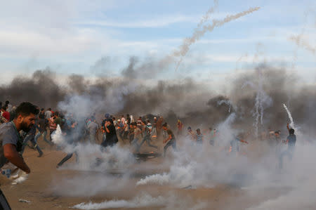 Palestinians run from tear gas fired by Israeli troops during a protest calling for lifting the Israeli blockade on Gaza and demanding the right to return to their homeland, at the Israel-Gaza border fence in the southern Gaza Strip October 5, 2018. REUTERS/Ibraheem Abu Mustafa