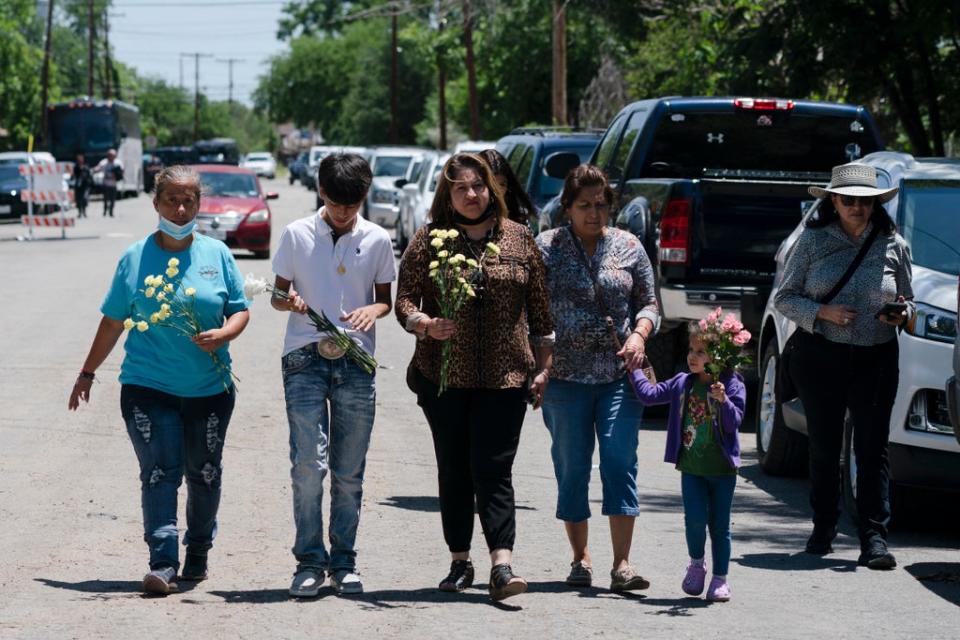 People walk with flowers to honor the victims in Tuesday’s shooting at Robb Elementary School (Copyright 2022 The Associated Press. All rights reserved)