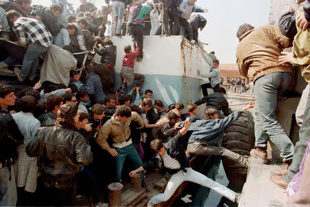 FILE PHOTO: Albanians scramble over an old fishing boat in a desperate bid to board a Greek frigate which docked in the port of Durres to evacuate Chinese and Iranian diplomats, March 15, 1997. Thousands of Albanians stampeded through police lines in their unsuccessful effort to reach the Greek naval vessel. REUTERS/Yannis Behrakis/File photo