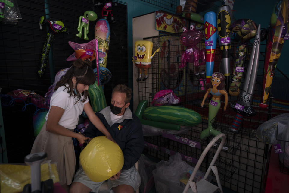 Abigail Ansdell, left, a 11-year-old daughter of Allan Ansdell Jr., owner and president of Adventure City amusement park, and food manager Clay Stark prepare balloons for decoration ahead of its reopening in Anaheim, Calif., Wednesday, April 14, 2021. The family-run amusement park that had been shut since March last year because of the coronavirus pandemic reopened on April 16. (AP Photo/Jae C. Hong)