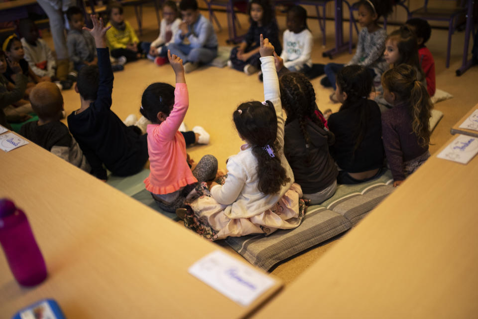 Children raise their hands as they attend class during the first school day at the Heembeek primary school in Brussels, Tuesday, Sept. 1, 2020. From Belgium to Russia, France to Hungary, tens of millions of kids return to school on Tuesday. While it can be a joyous time for youngsters, many parents and teachers are more than uneasy how that will fuel the continent's daily infection rates. (AP Photo/Francisco Seco)