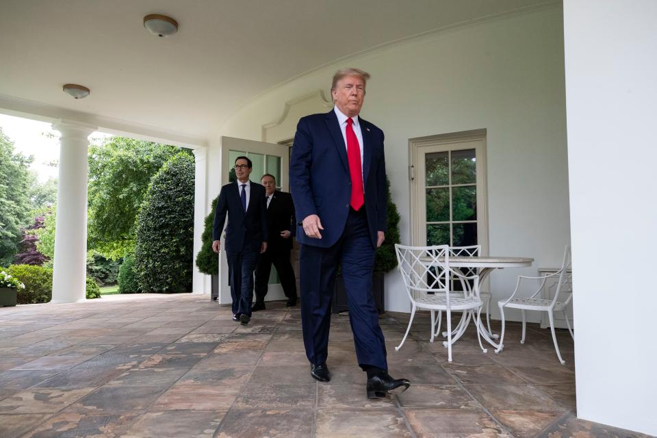 President Donald Trump walks out of the Oval Office followed by Treasury Secretary Steven Mnuchin and others, to speak in the Rose Garden of the White House on May 29, 2020.