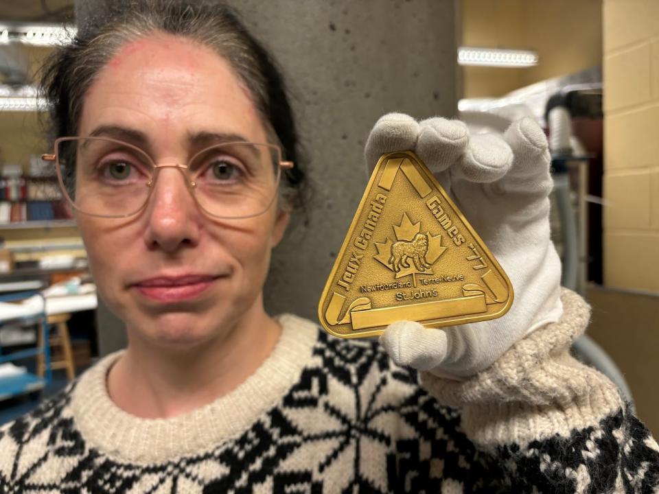 Maureen Peters, curator at The Rooms in St. John's, shows off a gold medal from 1977 Canada Games. In honour of the games returning in 2025, the museum is planning an exhibit celebrating the '77 games and the history of sporting in the province.