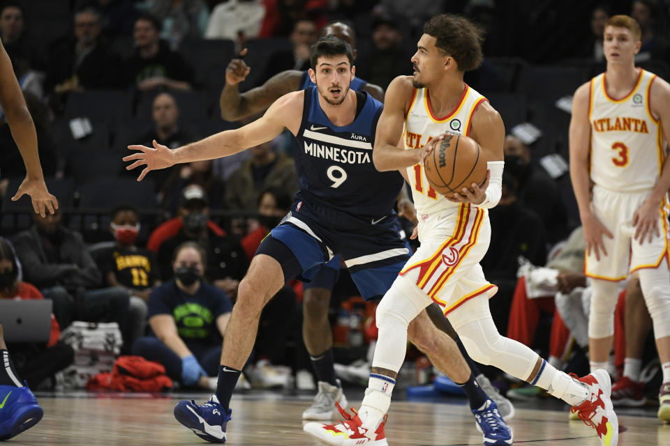 Atlanta Hawks guard Trae Young, front right, looks to pass around Minnesota Timberwolves guard Leandro Bolmaro (9) during the first half of an NBA basketball game Monday, Dec. 6, 2021, in Minneapolis. (AP Photo/Craig Lassig)