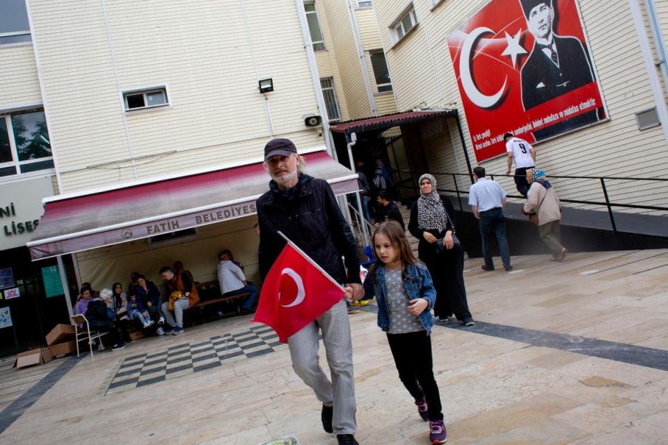 A voter and his child emerge from a polling station in Istanbul, Turkey in the second round of presidential elections. (Yusuf Sayman/For The Independent)