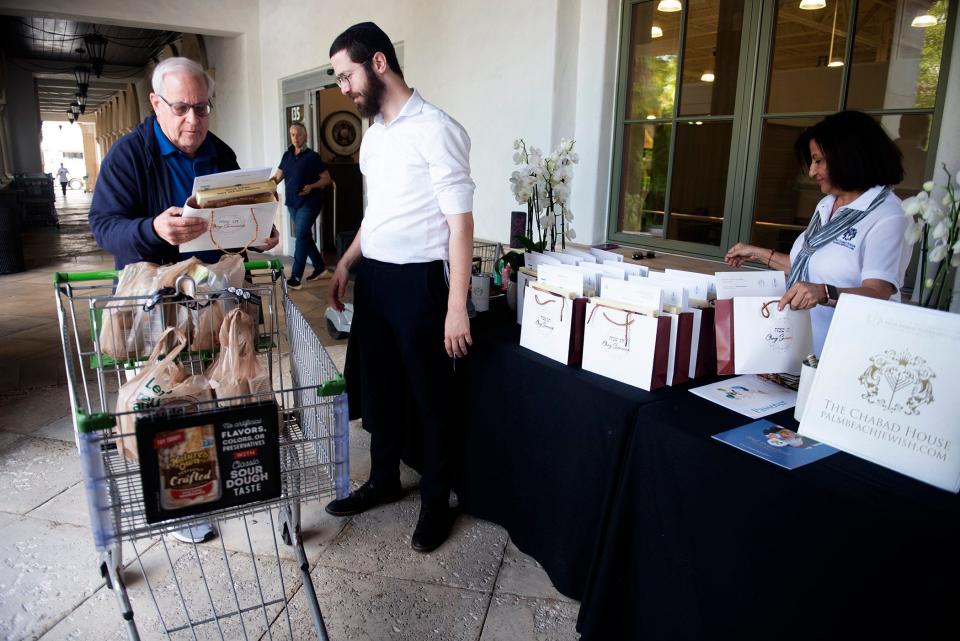 Publix customer Barry Schulman, left, of West Palm Beach, stops by the The "Passover at Publix" matzah table attended by Mendy Schochet and Eliza Tizabgar of Chabad House on Friday.