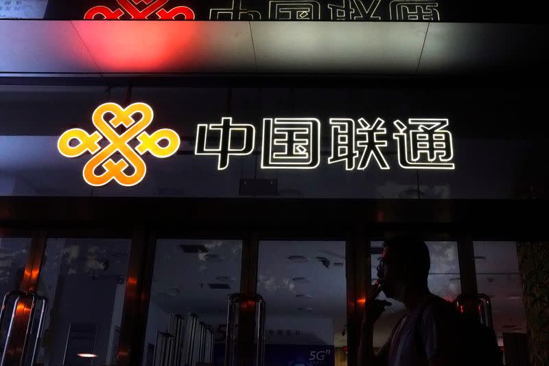 FILE PHOTO: Man smokes in front of a China Unicom store in Beijing