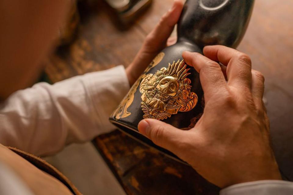 Close up of Clase Azul's Dia de los Muertos bottle that has gold designs on a black ceramic bottle