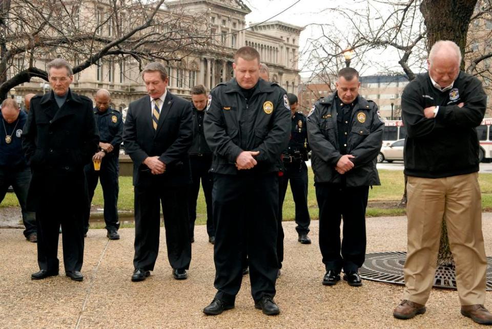 Deputy Chief Ozzy Gibson, center, bows his head in prayer during the Man Up sponsored prayer rally at the Police Memorial on 6th and Jefferson Streets to promote unity between the citizens of Louisville and the Police.   Dec. 24, 2014