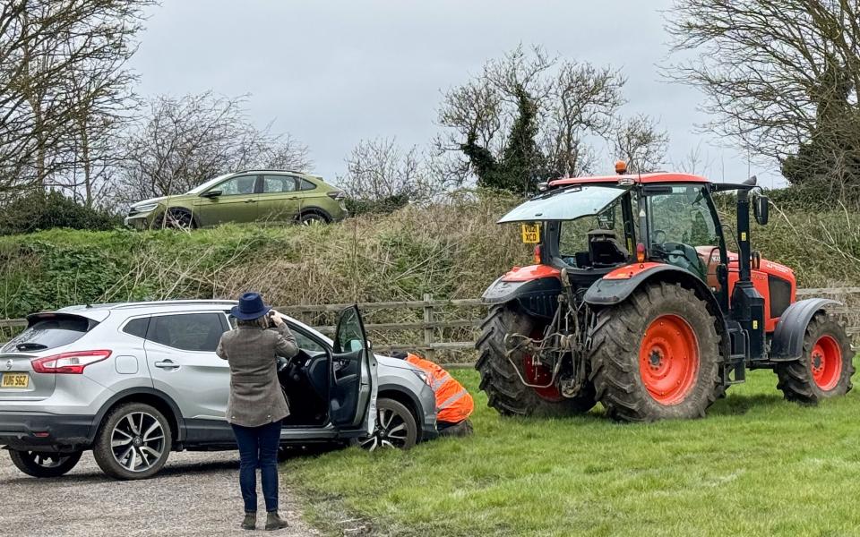 A tractor helps a stuck car out of the mud at Cheltenham