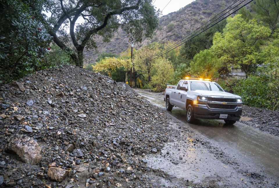 A vehicle makes its way around a mudslide covering part of Silverado Canyon Road in Silverado in eastern Orange County, Calif., as a winter storm brought heavy rain, high winds and flash flooding to Orange County and Southern California Tuesday, Dec. 14, 2021. (Mark Rightmire/The Orange County Register via AP)