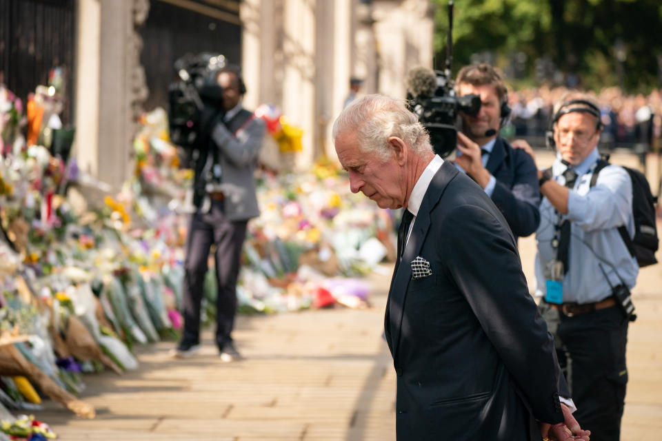 King Charles III looks at flowers outside Buckingham Palace, London after travelling from Balmoral following the death of Queen Elizabeth II on Thursday. Picture date: Friday September 9, 2022.