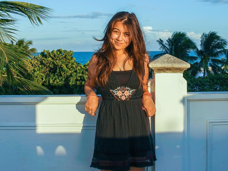 The author stands on a rooftop overlooking the ocean and palm trees