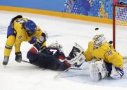 Team USA's Jocelyne Lamoureux is hauled down by Sweden's Lina Backlin (L) as Sweden's goalie Kim Martin Hasson sprawls to make a save during the third period of their women's semi-final ice hockey game at the 2014 Sochi Winter Olympics, February 17, 2014. REUTERS/Grigory Dukor (RUSSIA - Tags: OLYMPICS SPORT ICE HOCKEY)