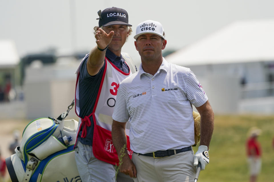 Chez Reavie, right, talks with his caddie Justin York before hitting a shot out of the rough on the 18th hole during the second round of the 3M Open golf tournament in Blaine, Minn., Friday, July 23, 2021. (AP Photo/Craig Lassig)