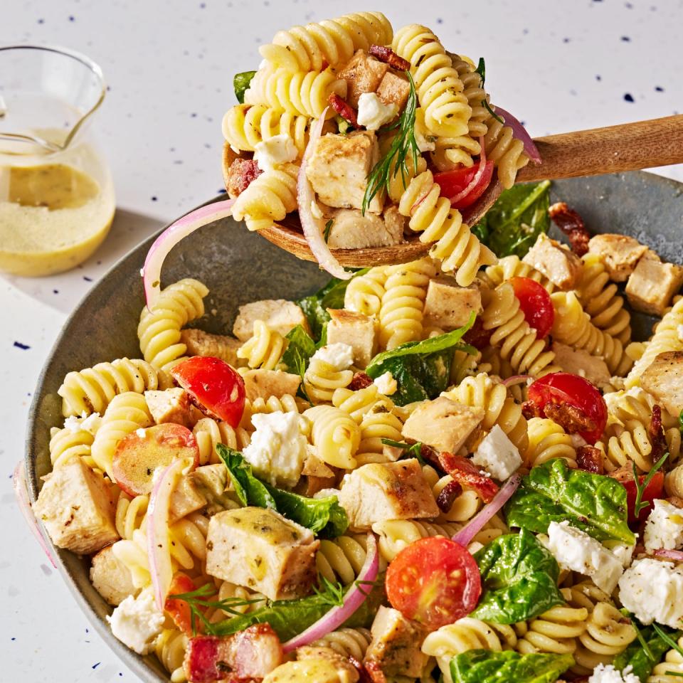 chicken pasta salad with tomatoes, sliced red onion, feta, basil, and bacon