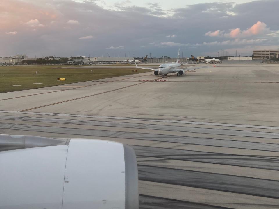 Looking out the window from the runway, the engine and another plane are shown.