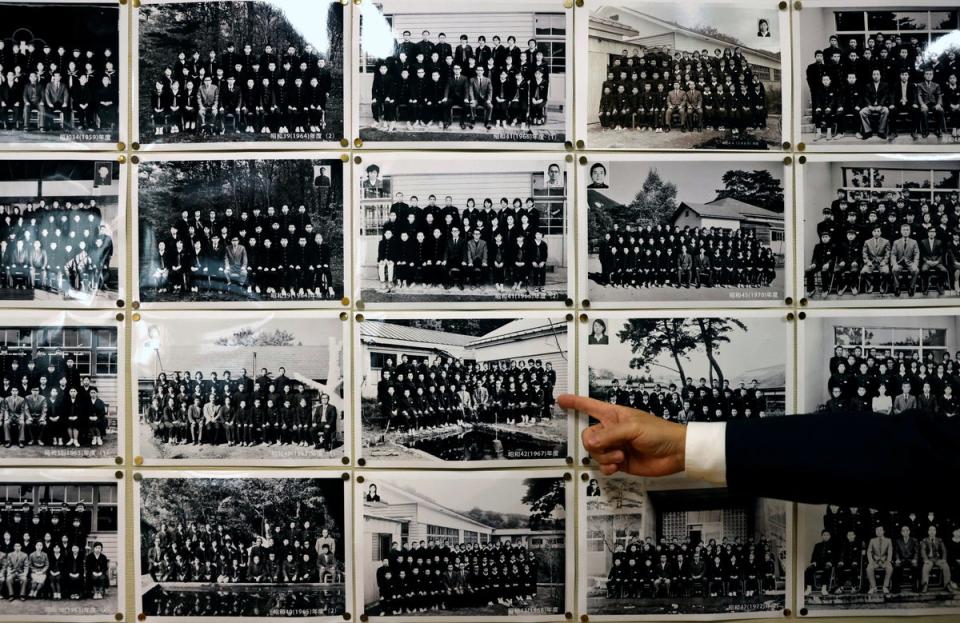 Yumoto Junior High School’s principal Mikio Watanabe, 54, points at old graduation photographs (Reuters)